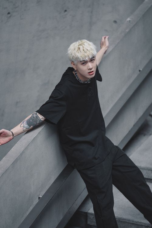 Free Blonde man with tattoos in a black t-shirt poses on stairs. Edgy fashion vibe. Stock Photo