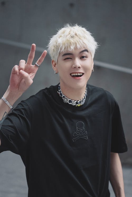 Young Man with Bleached Hair Showing a Peace Sign 