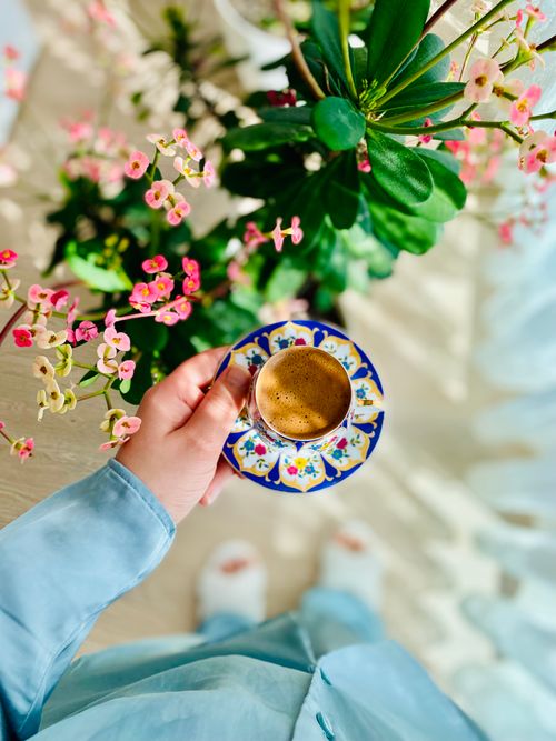 Free Top view of Turkish coffee in a decorative cup, held by a hand amidst vibrant flowers in Istanbul. Stock Photo