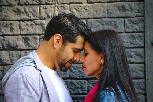Free Close-up portrait of a loving couple embracing in Mexico City against a stone wall. Stock Photo