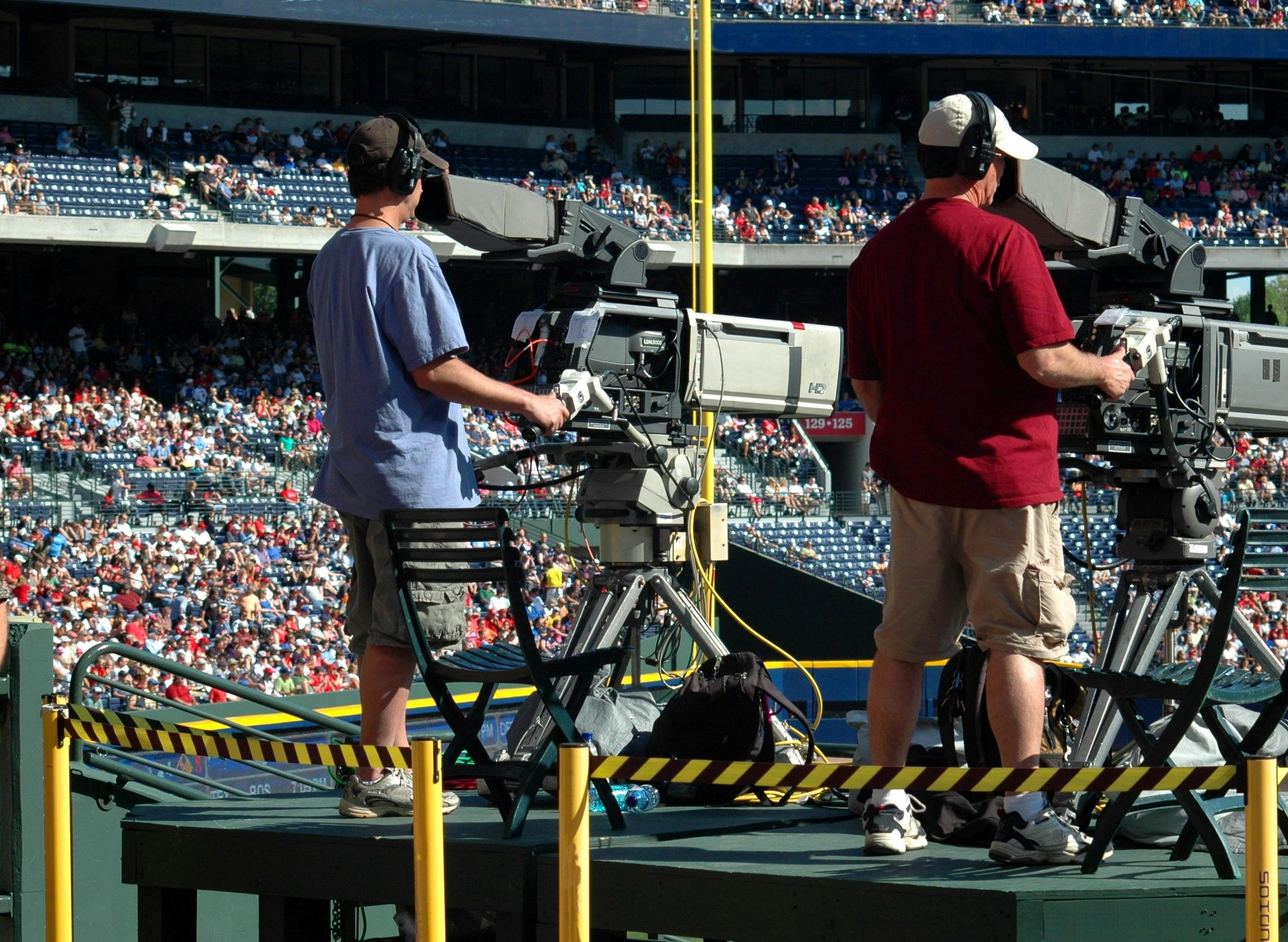 2 camera man standing in a green metal stage during daytime