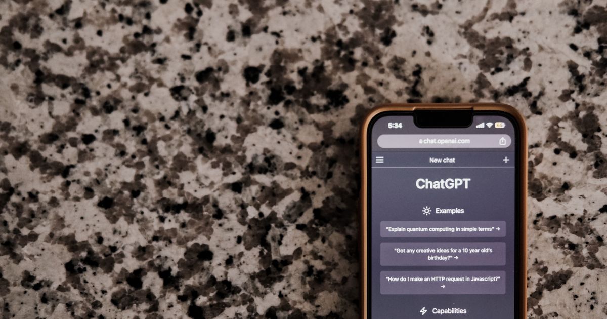 Close-up of a smartphone with the ChatGPT interface on screen, resting on a speckled surface