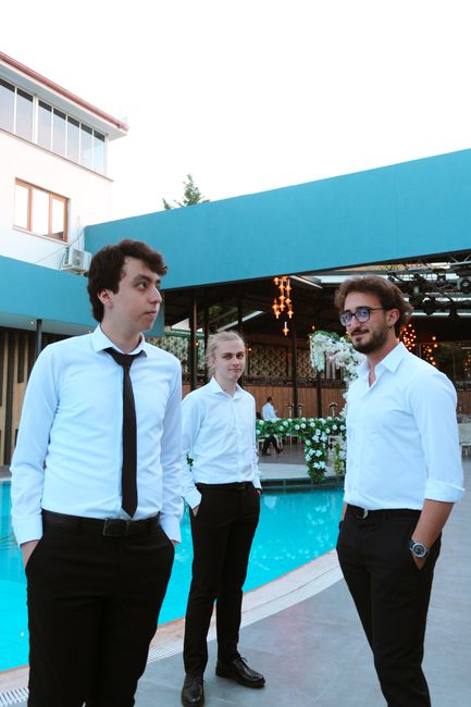 Three men in formal attire standing together at an outdoor venue near a pool. Three men in formal attire standing together at an outdoor venue near a pool.