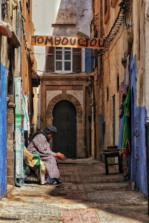 Man in a Gown and a Turban Sitting on a Bench in an Alley 