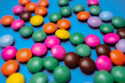 A vibrant assortment of colorful candies scattered on a bright blue background, perfect for sweet-themed projects.
