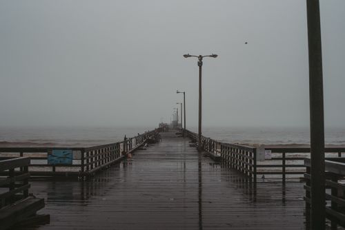 Free A long wooden pier extends into the misty, stormy sea under overcast skies. Stock Photo