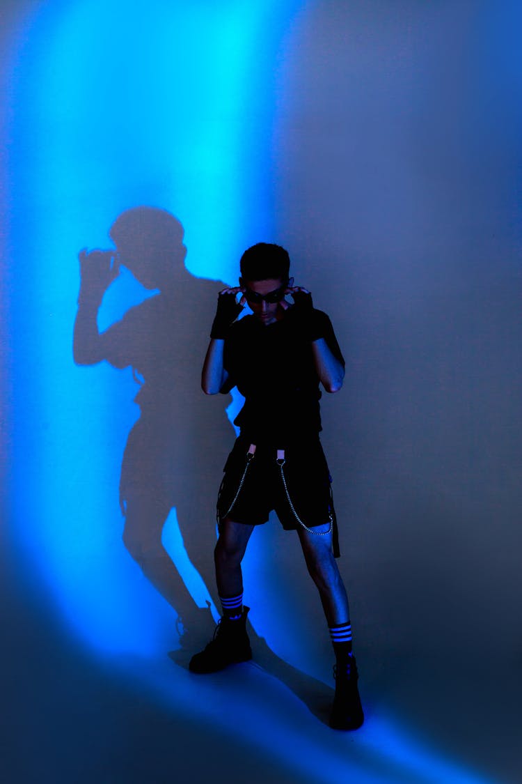 Man In Fighting Pose Casting Shadows On Blue Wall