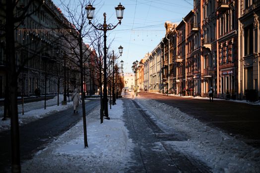 A picturesque winter scene on a historic city street with snow and warm sunlight.