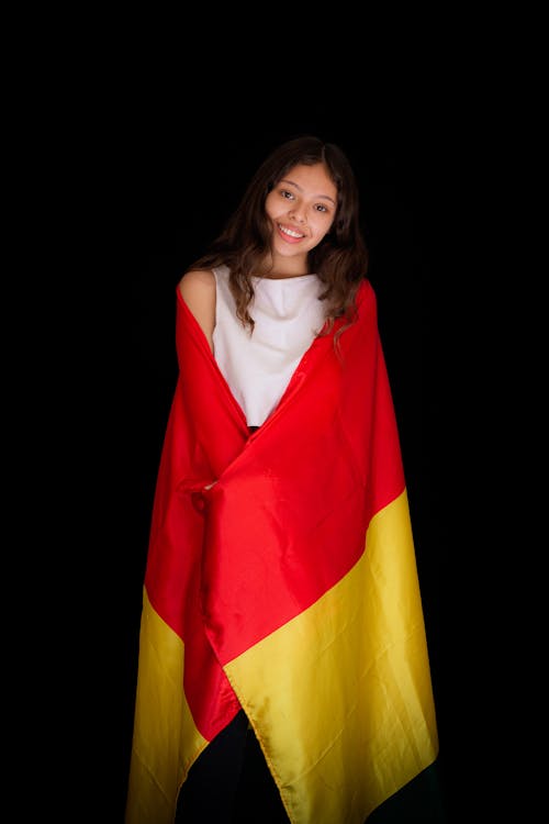 Studio Shot of a Young Woman Covered with a Fabric in Red and Yellow Colors 