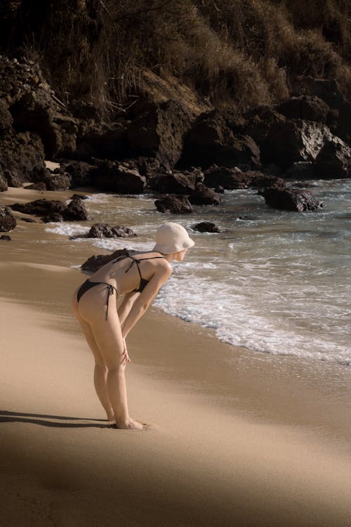 A woman in a bikini is standing on the beach