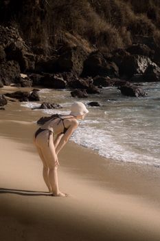 A woman in a black bikini and hat enjoys the beach at Puerto Escondido, Mexico.
