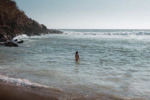 Free A peaceful beach setting with a lone swimmer in Puerto Escondido, Mexico. Stock Photo