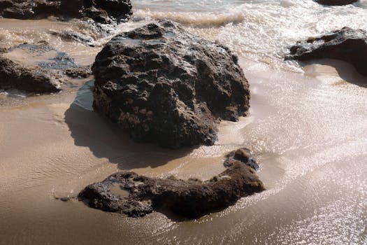Rugged rocks on the sandy beach of Puerto Escondido, Mexico at sunset.