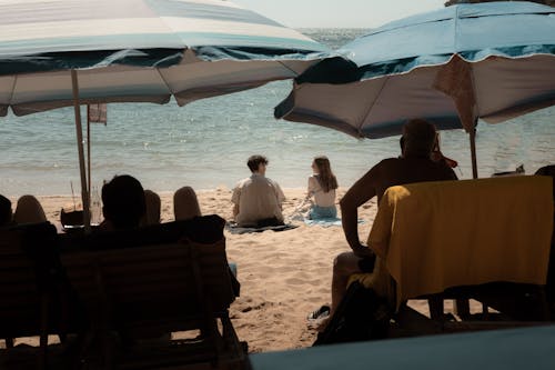 Free People sitting on the beach under umbrellas Stock Photo