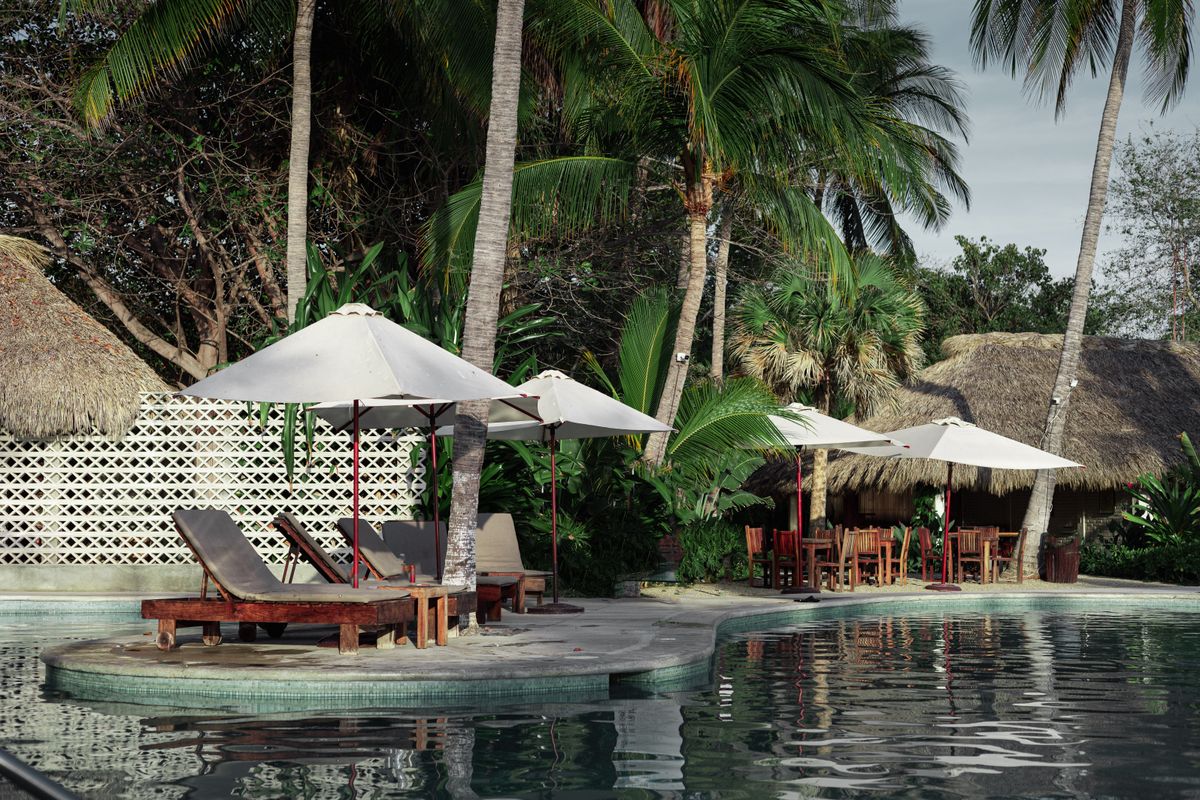Community swimming pool with lounge chairs and parasols at sunset
