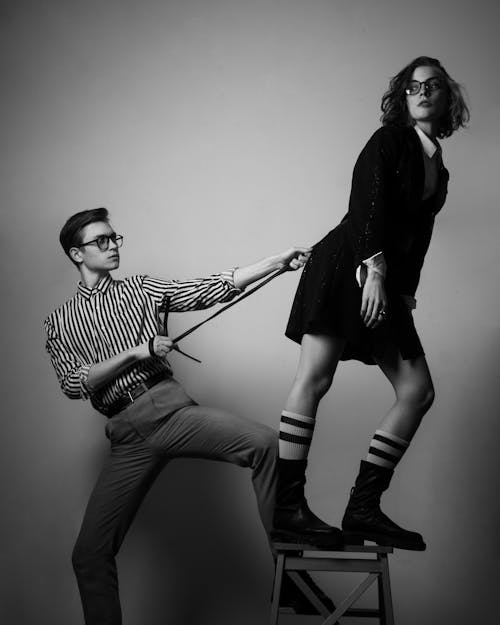 Man Holding Woman on Belt in Black and White