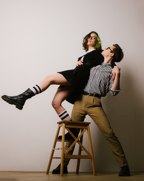 Free A fashionable couple striking a dynamic pose indoors with a minimalist backdrop. Stock Photo