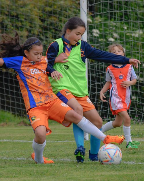 Free Three young girls actively playing a soccer match outdoors, showcasing team spirit and sportsmanship. Stock Photo