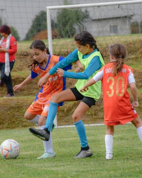 Young girls playing an intense soccer match outdoors on a grassy field, showcasing teamwork and athletic skills.