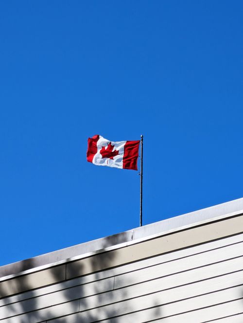 Free A Canadian flag waves on a rooftop against a bright blue sky in Halifax, NS, Canada. Stock Photo
