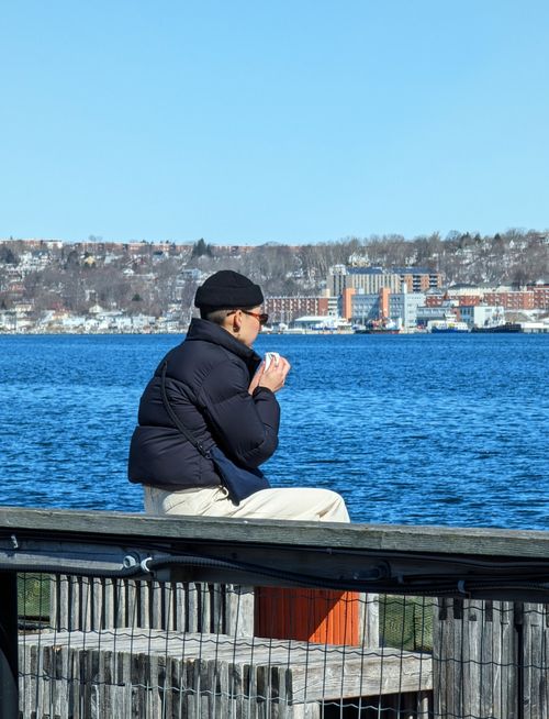 Free Woman sitting by Halifax waterfront with scenic view. Stock Photo