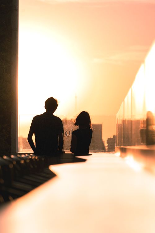 Free Silhouetted couple enjoying sunset view from an urban rooftop in Buenos Aires. Stock Photo