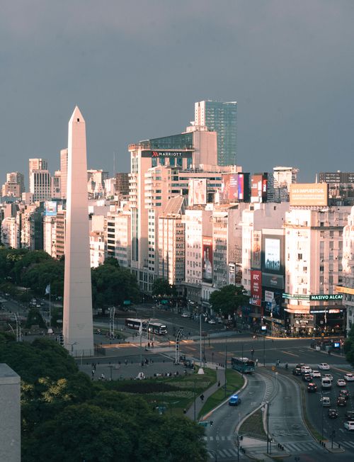 Free Aerial view of the Obelisk in Buenos Aires surrounded by city buildings and traffic at dusk. Stock Photo