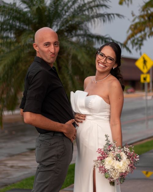 Free A playful couple poses, the woman in a wedding dress holding flowers, in Mérida, Mexico outdoors. Stock Photo