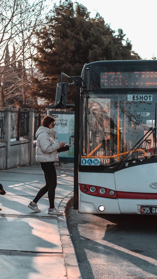 Free A woman in a jacket boards a public bus in Izmir, Turkey during the day. Stock Photo