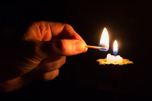 Personne Tenant Le Bâton D'allumette Avec Le Feu Devant La Bougie Avec Le Feu