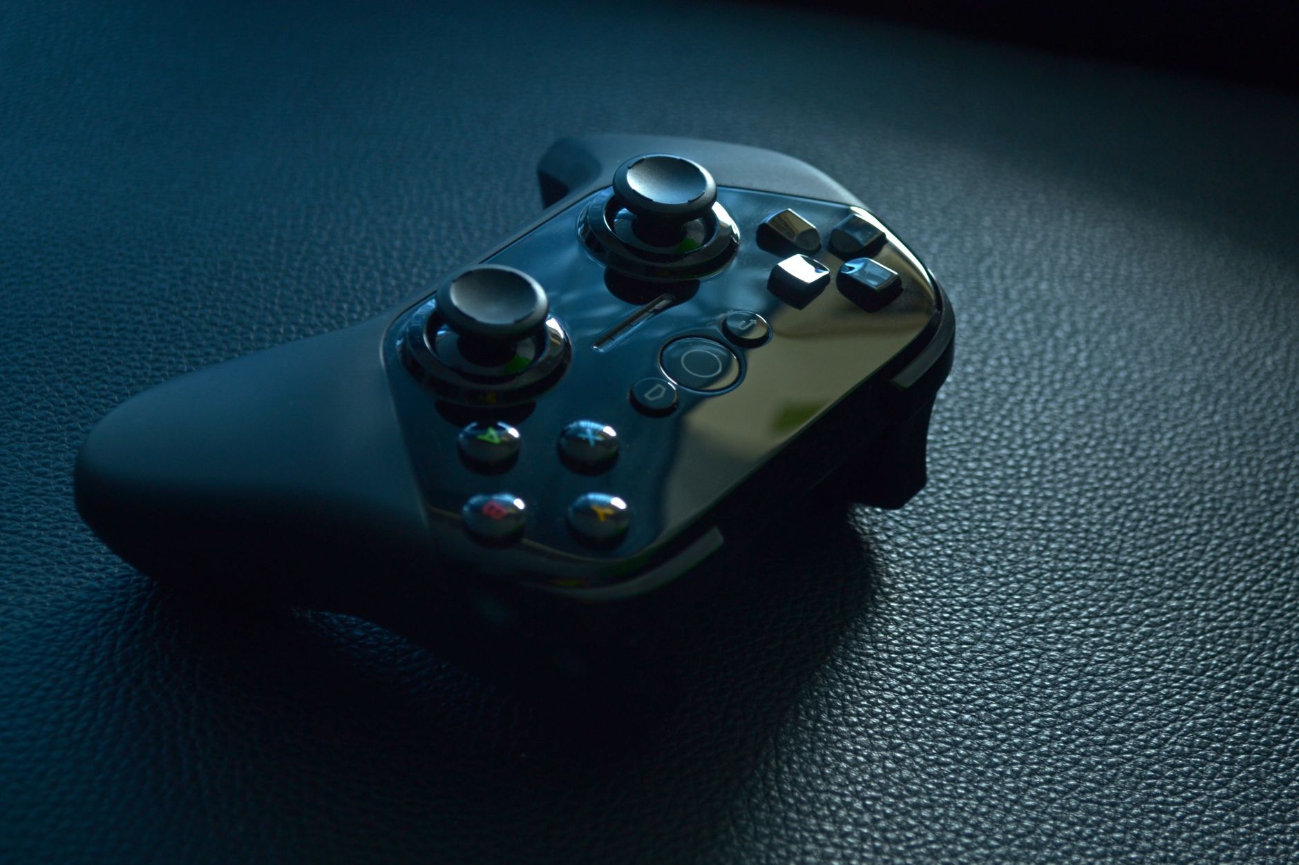 Close-up of a modern wireless gaming controller on a dark textured surface.