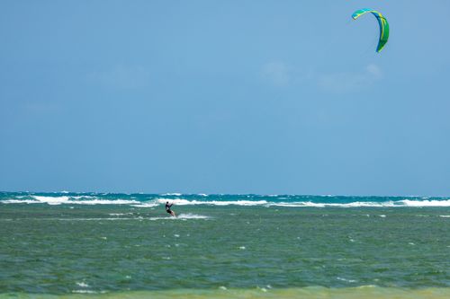 Free A kitesurfer rides the waves under a clear blue sky, enjoying an adventurous day at sea. Stock Photo