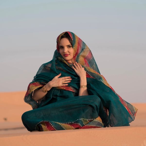 Woman in patterned shawl on desert sand, photo by Ben Khatry on Pexels