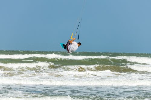 Free Experience the thrill of kitesurfing as a man skillfully navigates ocean waves under a clear blue sky. Stock Photo