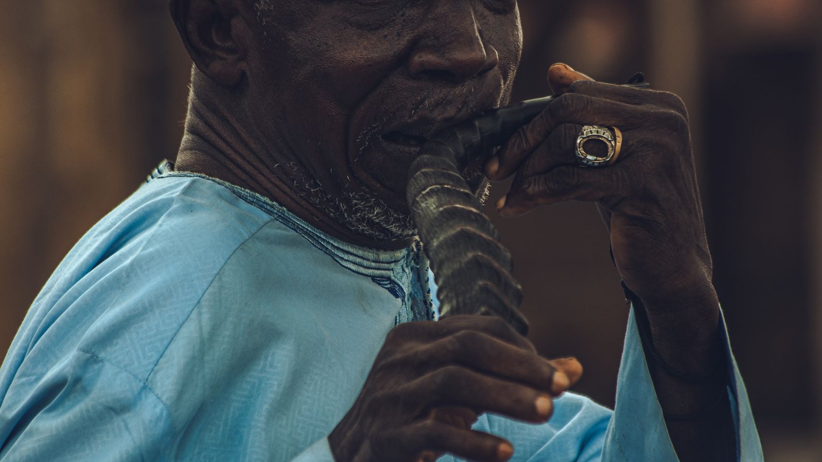Man in traditional clothing playing an instrument, Senegal