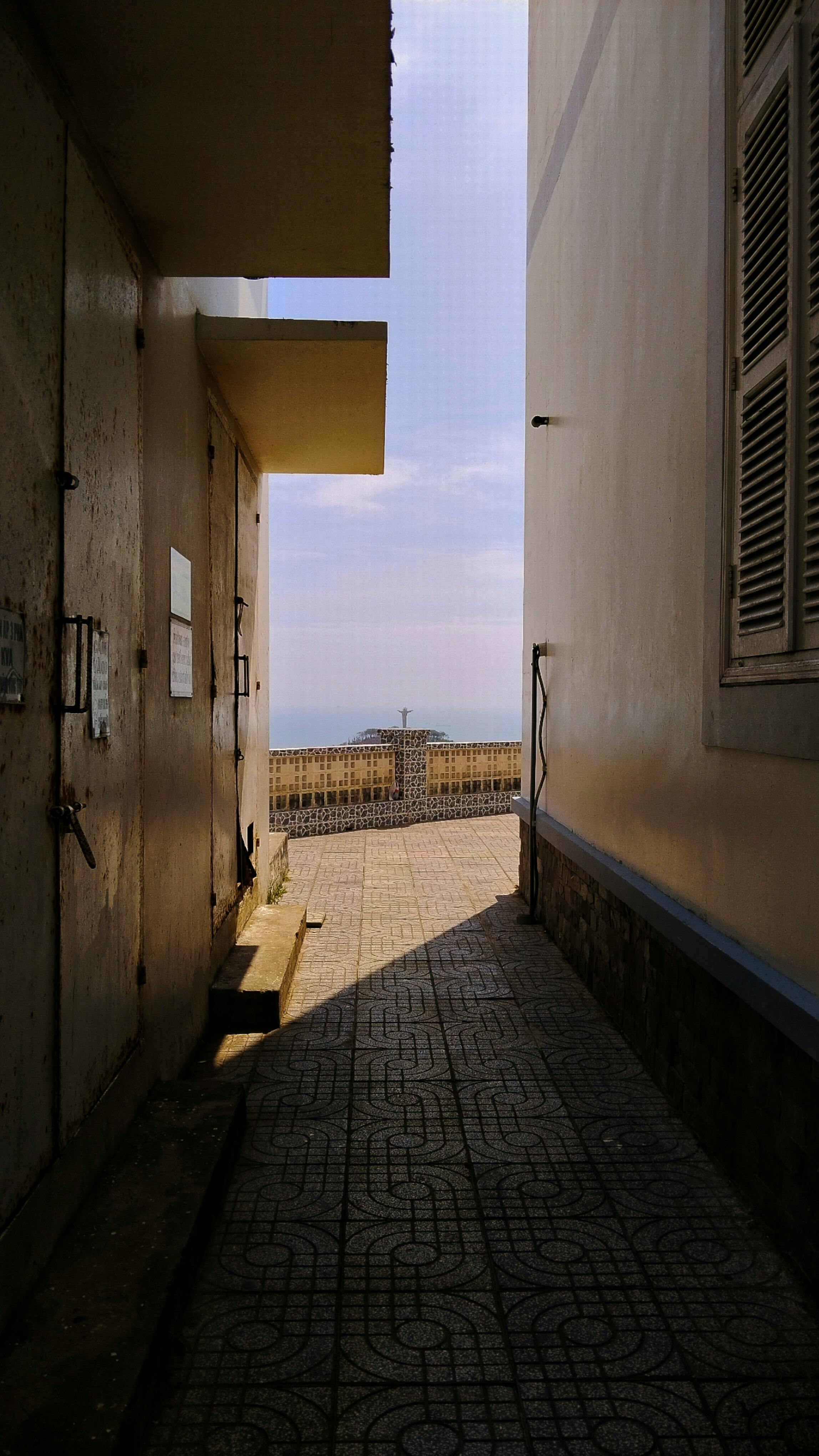 A narrow alley in Vũng Tàu reveals a scenic ocean view, framed by traditional architecture.