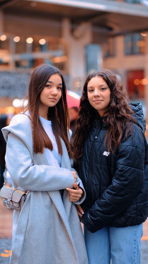 Free Two teenage girls smiling while standing outdoors in stylish winter clothing. Stock Photo
