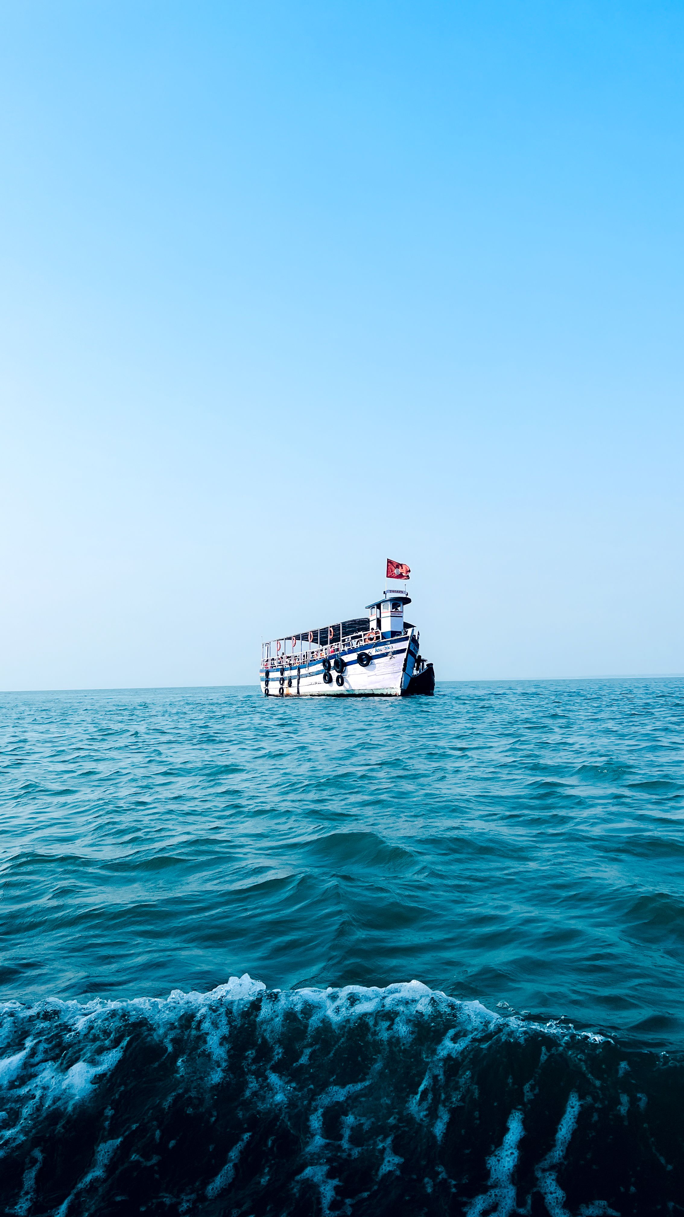 Scenic view of a ship sailing calmly on the open sea under a clear blue sky in Udupi, India.