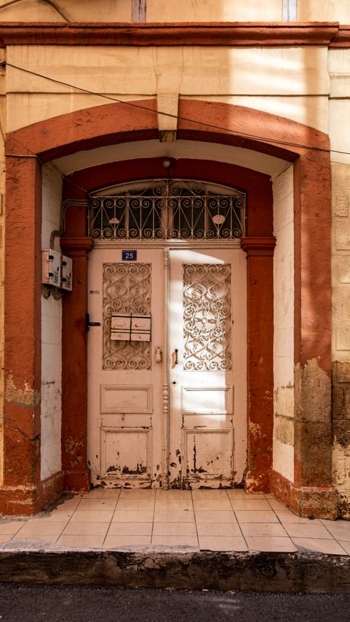 Free A rustic wooden door with decorative ironwork, framed by an aged facade, reflecting vintage architecture. Stock Photo