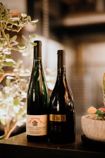 Two elegant wine bottles elegantly displayed with plants in a relaxed indoor atmosphere.