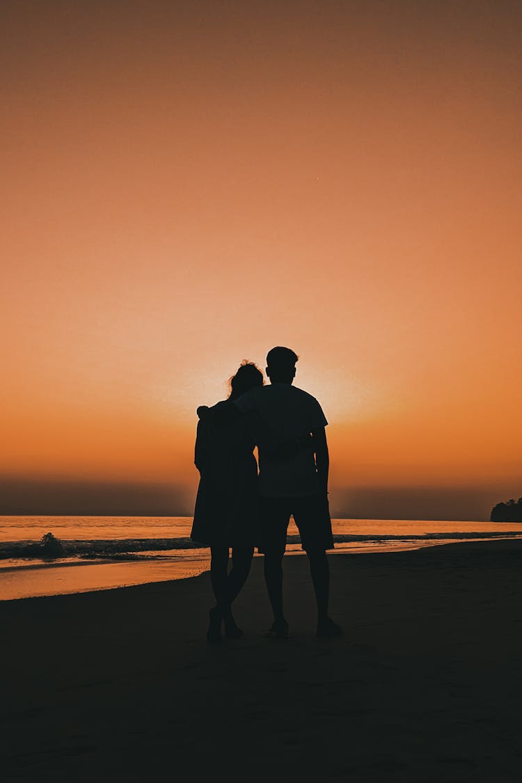 Silhouette Of A Couple Standing On A Beach 