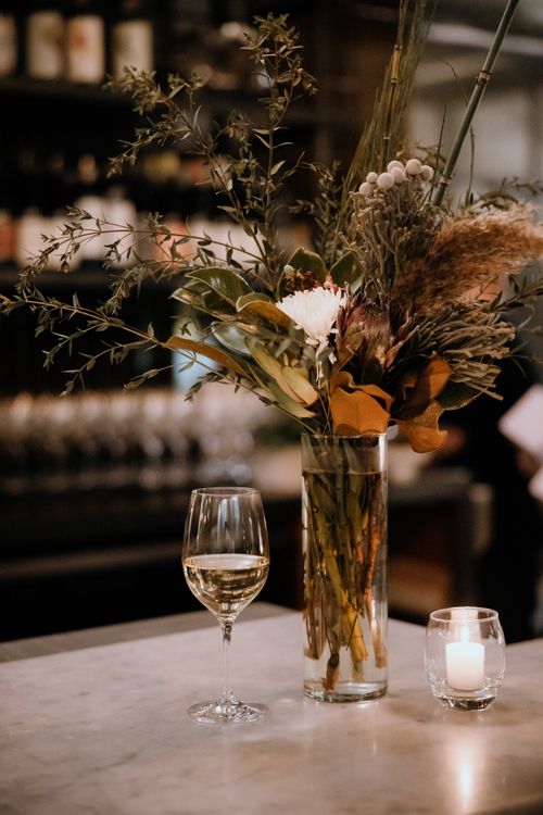 Free A stylish bar scene with wine glass, floral centerpiece, and warm lighting for a cozy ambiance. Stock Photo