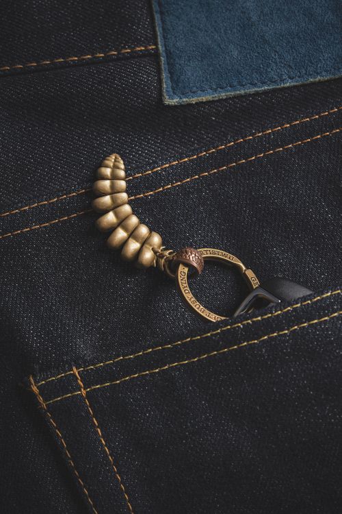 Free Close-up of a golden metallic dragon keychain tail in a denim pocket. Stock Photo