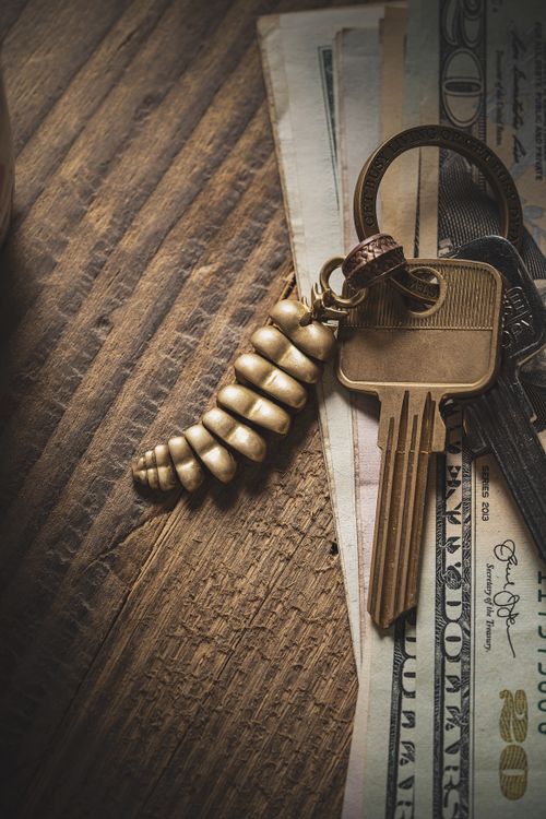 Free A golden keychain and keys on US dollar bills on a rustic wooden surface. Stock Photo