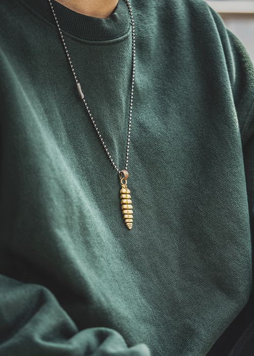 Free A stylish gold pendant necklace resting on a cozy green sweater in a close-up shot. Stock Photo