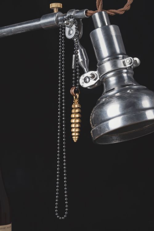 Free A close-up of a vintage industrial-style lamp with a gold pendant on a black background. Stock Photo