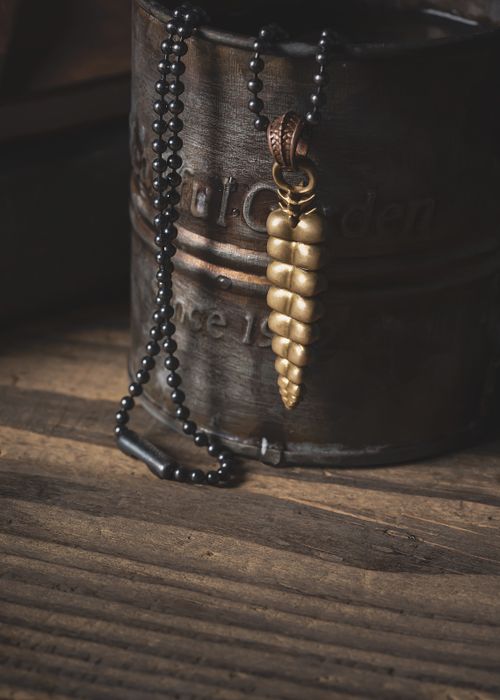 Free Close-up of a vintage golden pendant with a black beaded necklace, placed against a wooden backdrop for an antique feel. Stock Photo