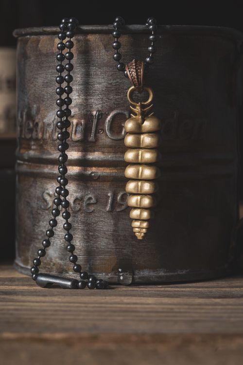 Free Close-up of a vintage golden necklace pendant draped over a rustic mug. Stock Photo