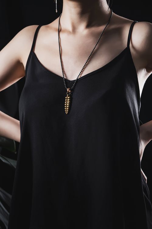 Free Close-up of a woman's black dress and golden necklace in an elegant fashion pose. Stock Photo