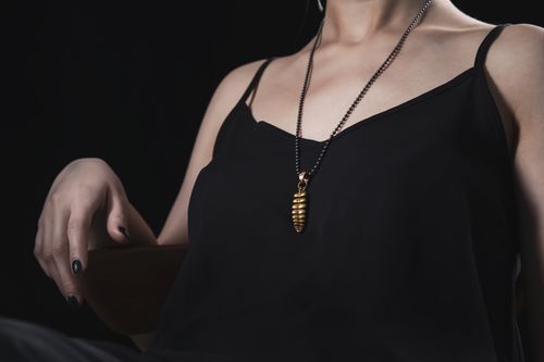 Free Close-up of a woman in black attire with a stylish gold pendant necklace. Stock Photo